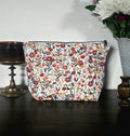 Floral-patterned pouch on a dark surface with a light background