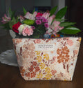 Floral-patterned bag with 'Southern Stitchery' label holding a bouquet of flowers.