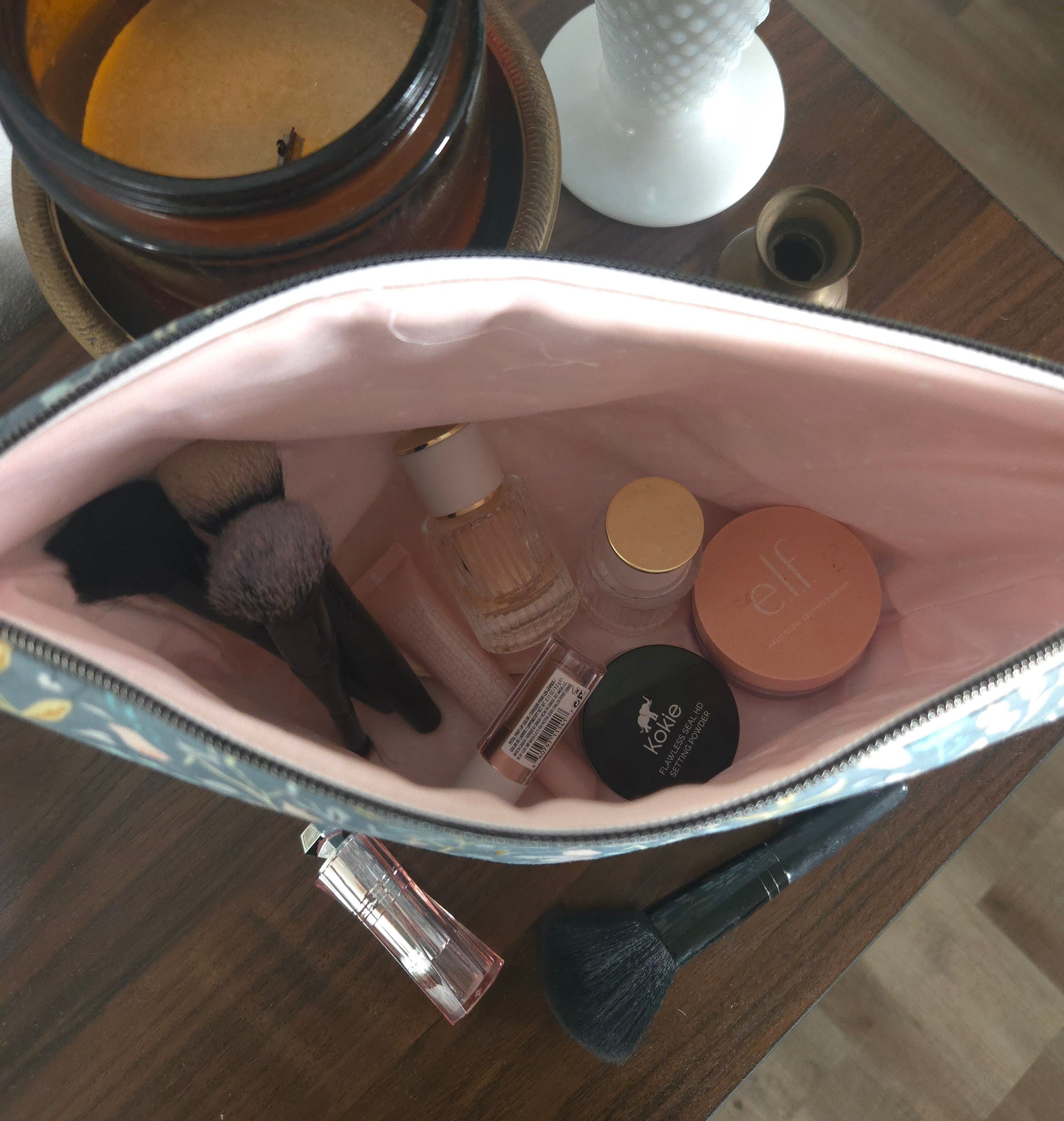 Makeup bag with cosmetic items on a wooden surface