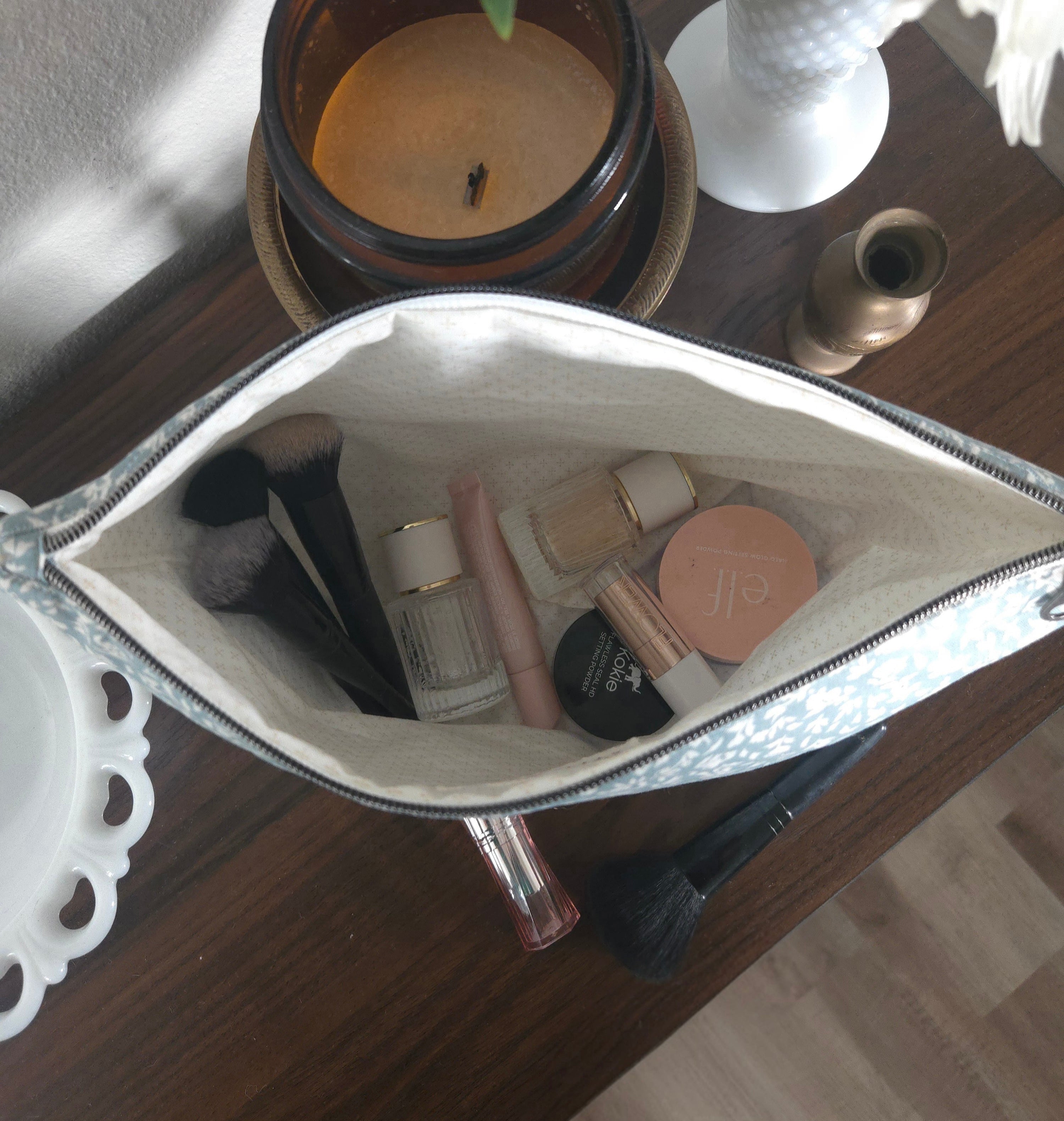 Makeup bag with cosmetic items on a wooden surface